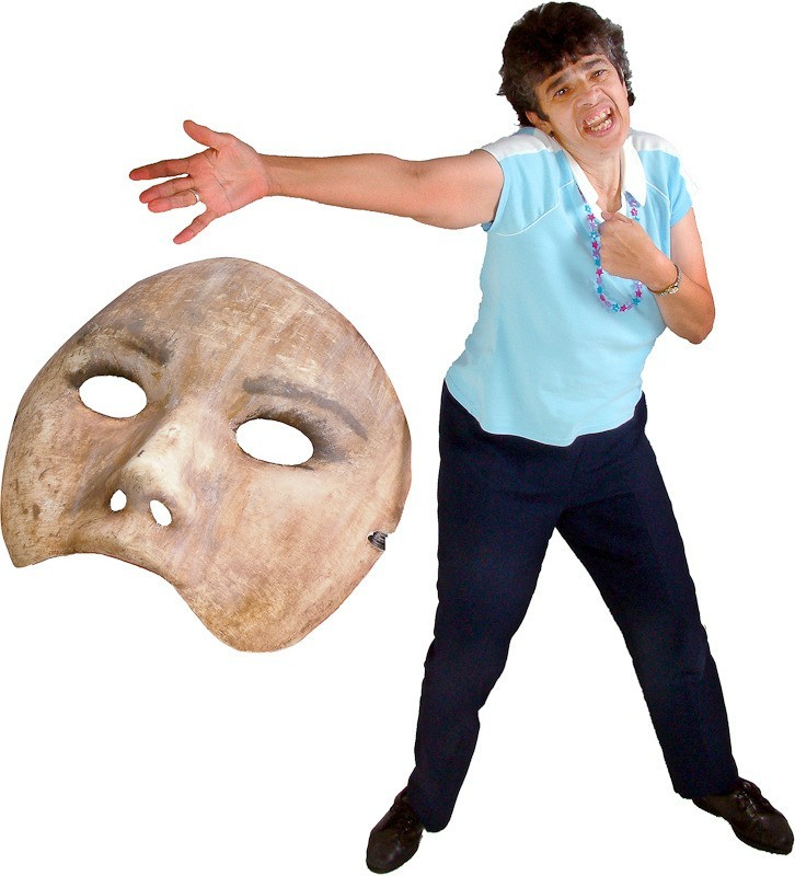 A woman being expressive with her arm out wide and singing. Next to her is a theatrical face mask.