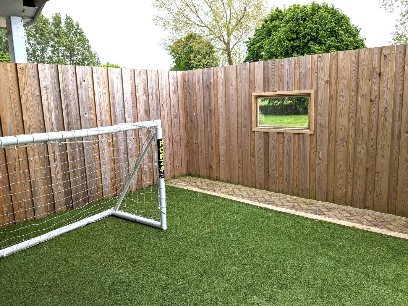 Fenced garden area with grass and a set of goal posts.