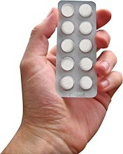 Close up of a hand holding a strip of tablets