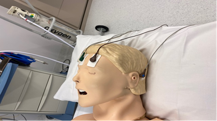 A dummy head with stickers attached to forehead and behind the ear