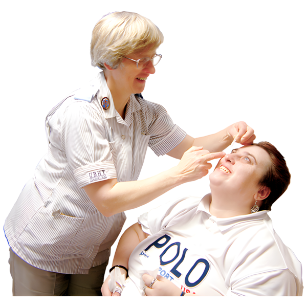 A nurse smiling while providing care to a seated patient.