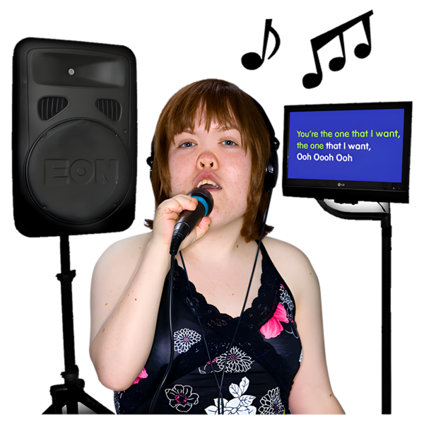 A woman singing with a microphone, speaker, and lyrics on a monitor.