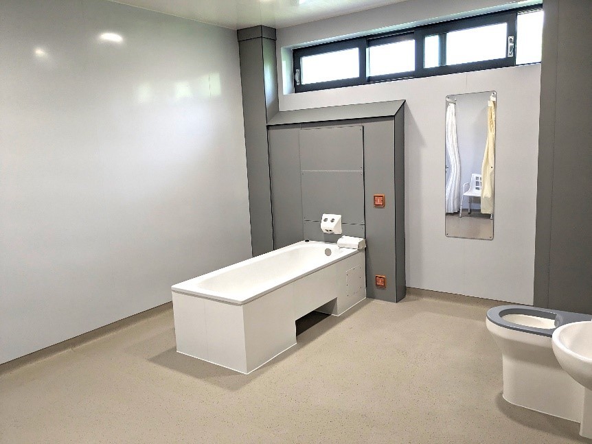 A large bathroom with a bath, mirror, toilet and sink