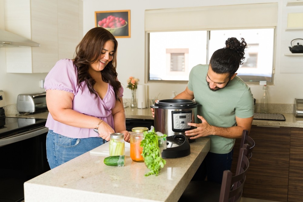 Happy man and woman cooking together using a slow cooker