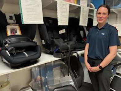 A member of staff standing in front of a range of child car safety seats