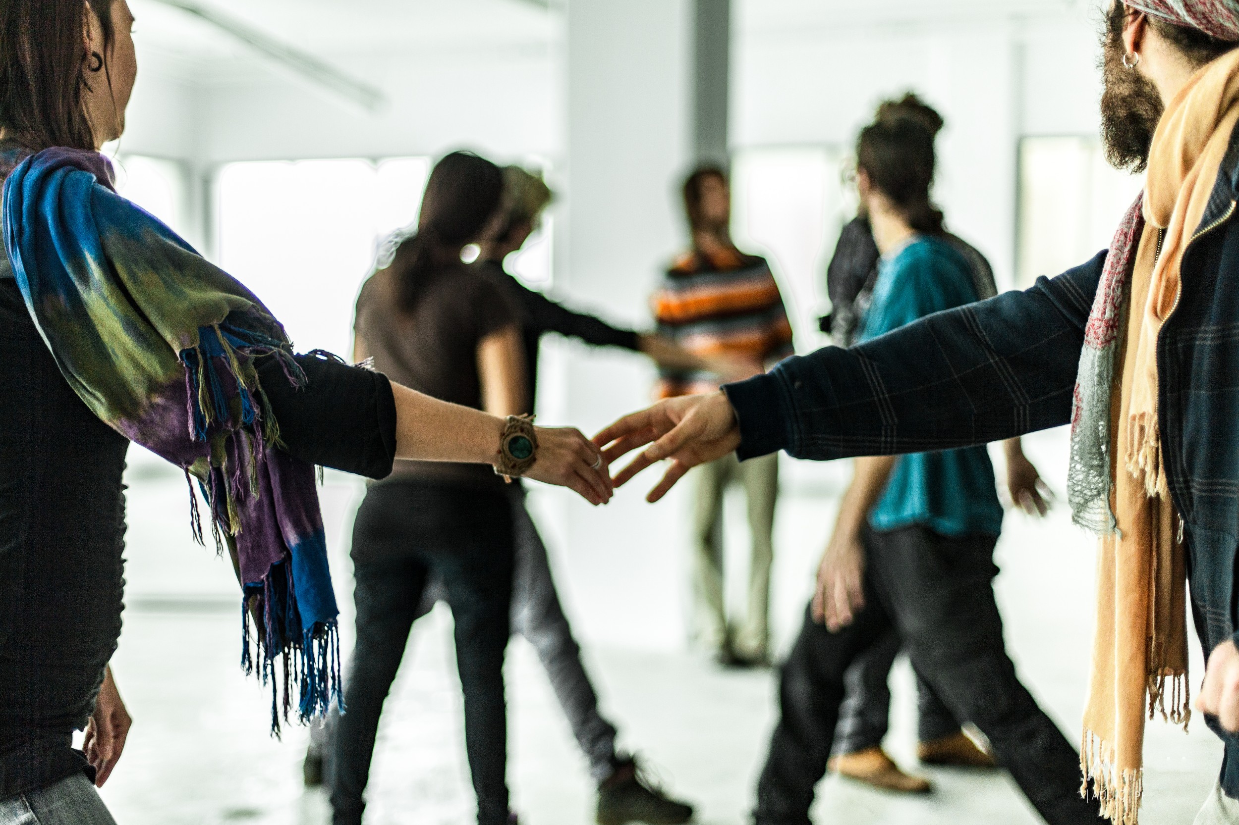 Man and woman touch hands while dancing. A group of people in the background.