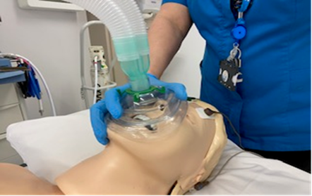 A dummy head with a nurse holding an oxygen mask over the mouth and nose