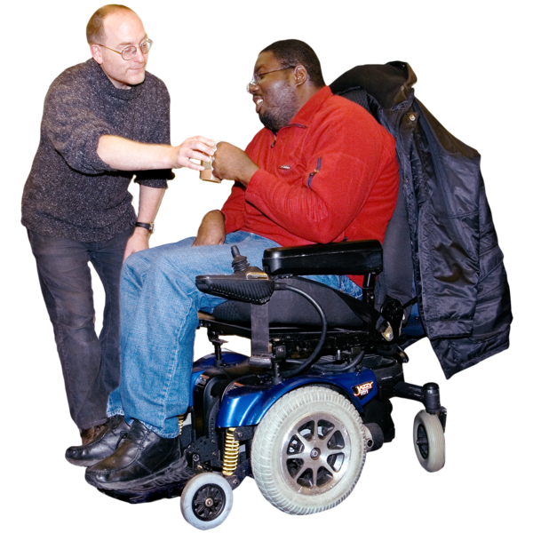Two men interacting, one standing and one seated in a wheelchair.