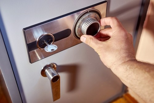 A large metal safe with a close up of a persons hand locking it
