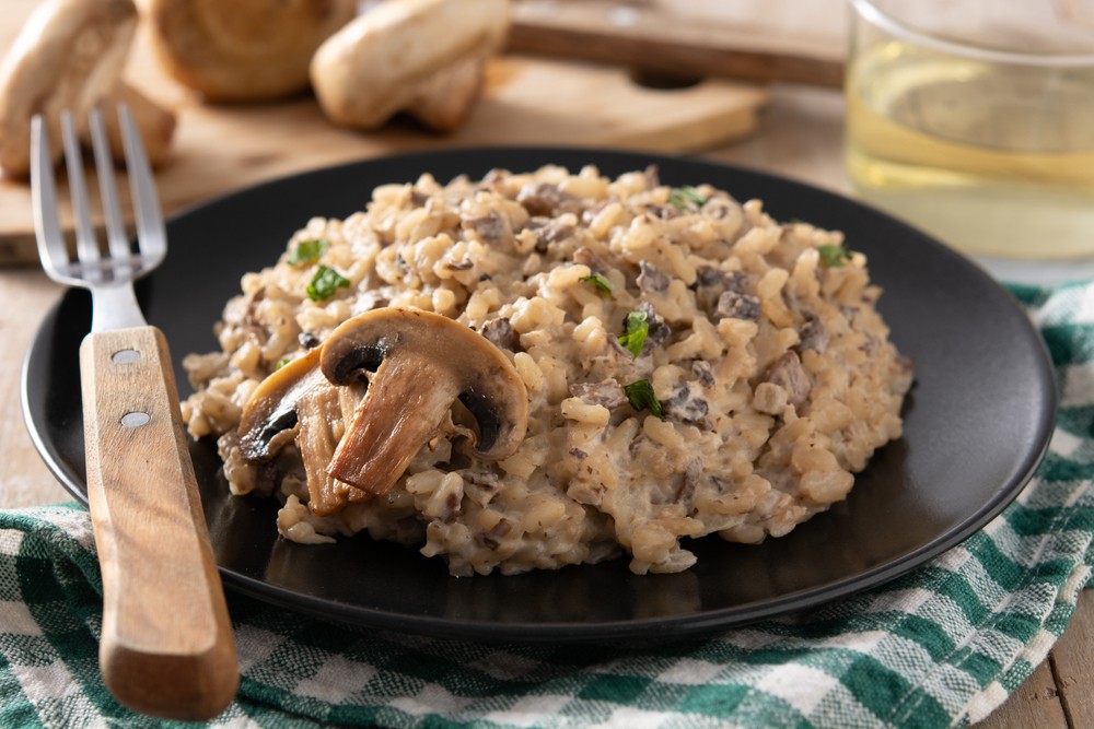 Close up of Mushroom risotto on black plate with a fork on the side