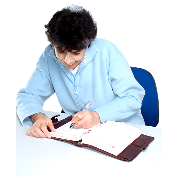 Person in blue fleece jacket writing in a brown planner at a white desk.