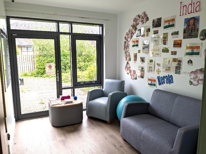 A room with a sofa, armchair and coffee table and patio doors.