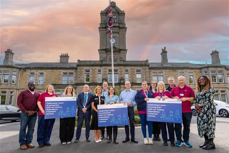 The Tobacco Dependency Treatment Service staff holding up banners celebrating 3 years of saving lives.